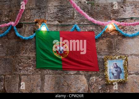 Portuguese flag next to a portrait of Saint Anthony at the Festas dos Santos Populares, Lisbon, Portugal. Stock Photo