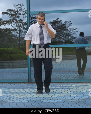 Businessman using a mobile phone in front of a corporate building. Stock Photo