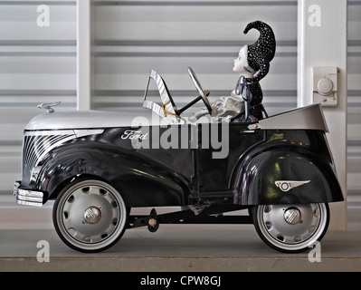 Antique child's toy pedal car with female driving figurine Stock Photo