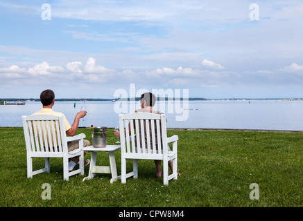 Two senior people in patio chairs drinking champagne by Chesapeake bay, USA Stock Photo
