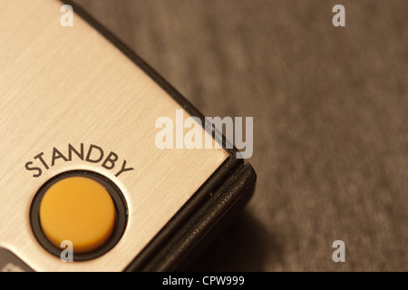 A close up of the yellow standby button on a remote control Stock Photo