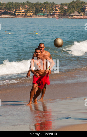 Mexico, Puerto Vallarta. Playing football on Playa Los Muertos beach, Puerto Vallarta, Mexico. Stock Photo