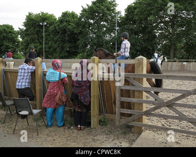 Muslim family watch horse riding instructor at a farm in Essex, UK Stock Photo