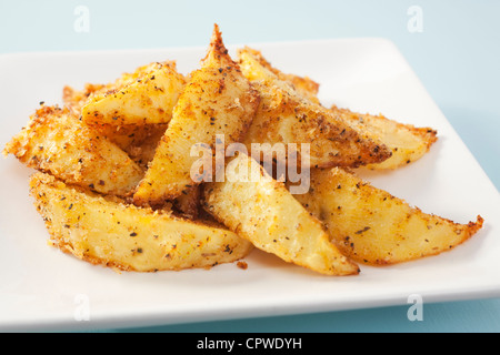 Crisp potato wedges with cajun seasoning, fresh from the oven, on a white plate. Stock Photo