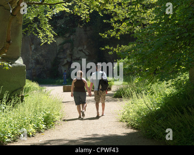 A man and a woman walk hand in hand through the Quarry Garden at Belsay Hall Northumberland in Spring sunshine Stock Photo