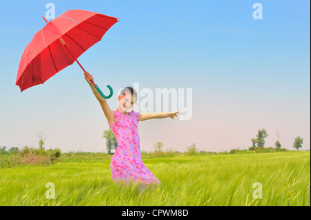 teenage girl with red umbrella in wheat field Stock Photo