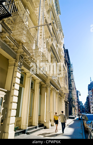 Couple walking by cast iron architecture on Greene Street in SOHO neighborhood, New York City. Stock Photo