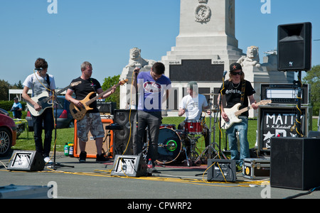 A small band playing their music on Plymouth Hoe, with guitars and amplifiers and a drum kit. Stock Photo