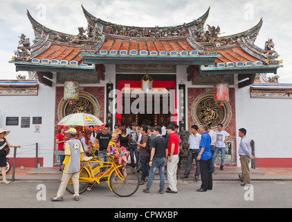 Colourful cycle rickshaw with tourists, Cheng Hoon Teng (Green Clouds temple) Temple, Malacca, Malaysia. Stock Photo