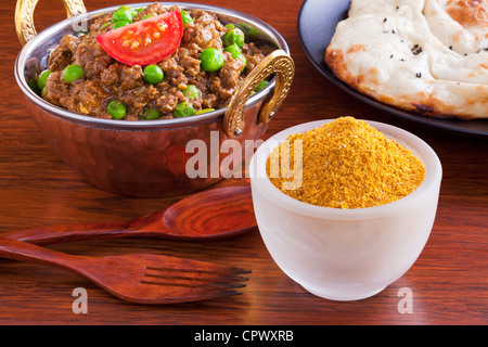 Curry powder with a beef mince curry, keema matar with peas, and naan bread. Stock Photo