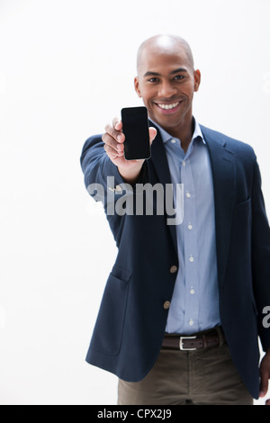 Portrait of African American man holding cellphone, studio shot Stock Photo