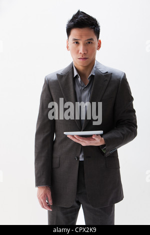 Young Asian businessman holding digital tablet, studio shot Stock Photo