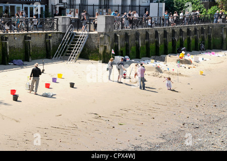 Small area of low tide sandy beach beside River Thames used by men creating sand sculptures hoping for donations from visitors Stock Photo