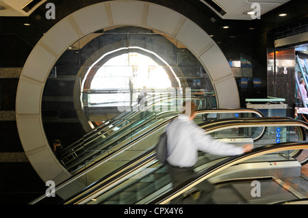 Motion blur of man on escalator passing large circular stone feature Westminster WC2 London England UK Stock Photo
