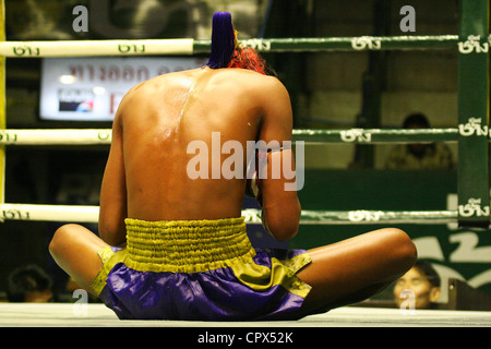 A boxer sits in the rings and concentrates on pre-fight rituals at the Rajadamnern Muay Thai Stadium in Bangkok, Thailand. Stock Photo