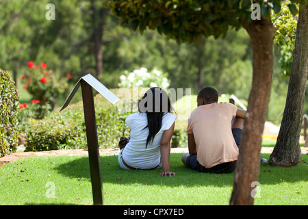 Young African couple sitting on grass, looking at a view Stock Photo
