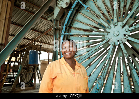 Female black factory worker stands in construction yard smiling at camera Stock Photo
