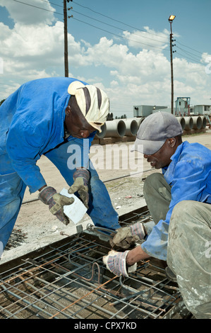 Two black factory workers lay bricks in a construction yard Stock Photo