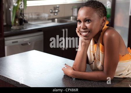 Young adult funky black female standing in a kitchen smiles at camera Stock Photo