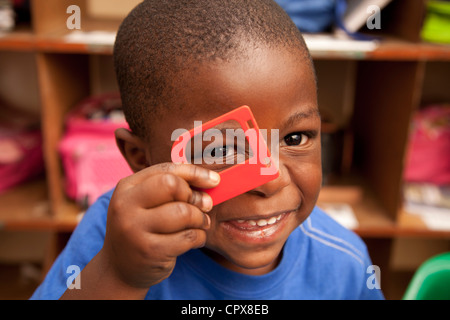 Child looking through toy frame, smiling Stock Photo