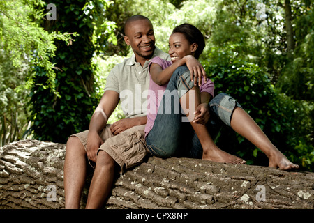 Closeup portrait of a young black couple, sitting on a tree, smiling Stock Photo