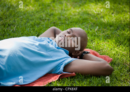 A young African man sleeping on the grass in a park Stock Photo