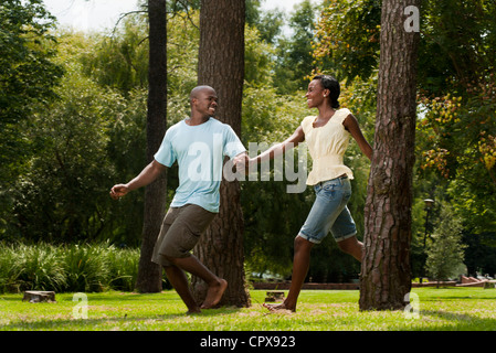 Young African couple running together through a park Stock Photo