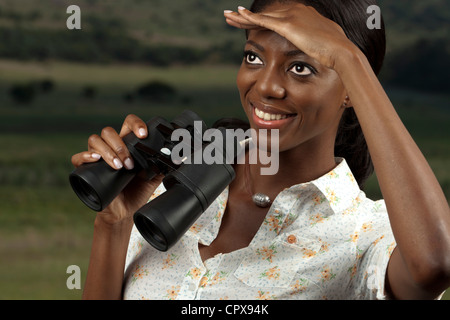 An African woman searches for game while holding binoculars Stock Photo