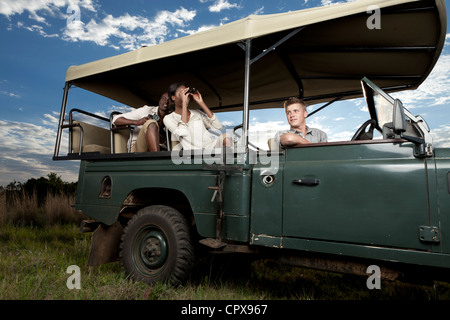 An African couple sitting in a game viewing vehicle searching for animals Stock Photo