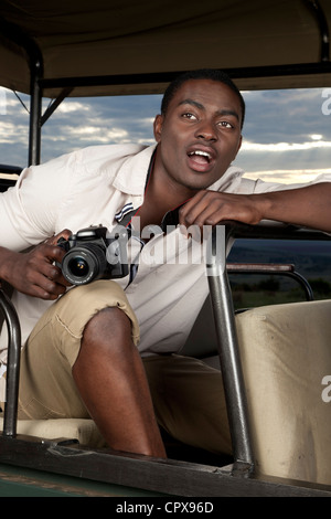 An African man sitting in a game viewing vehicle looking surprised Stock Photo