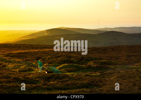 A couple wild camping on the top of Moel Famau overlooking the Clwydian Range towards Pennycloddiau and Moel y Parc Stock Photo