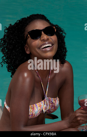 Young black woman lying on a deckchair next to a pool Stock Photo