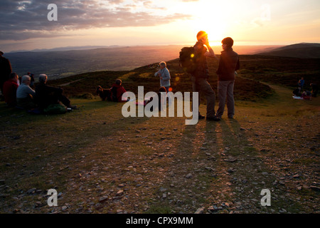 Hill walkers at Moel Famau the highest peak in the Clwydian Range at sunset enjoying the landscape and view of vale of clwyd Stock Photo