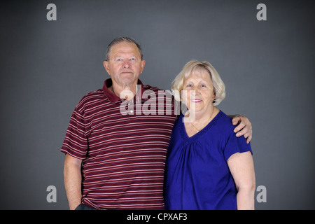 Happy and healthy senior couple looking at camera, studio shot over grey background. Stock Photo