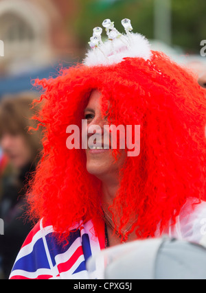 Woman in parade wearing red wig with white crown and union jack flag, Abergavenny, Wales, UK Stock Photo