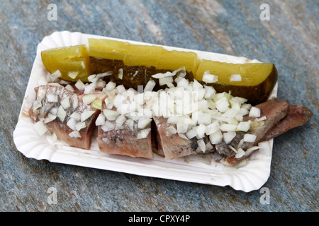 A traditional Dutch delicacy of raw herring with chopped onions and pickles Stock Photo
