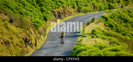 Tourist cycling along country road through Cumbrian mountains in Lake District National Park, UK Stock Photo