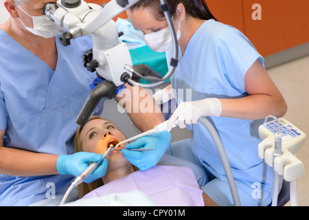 Dentist operating female patient through microscope at surgery office Stock Photo