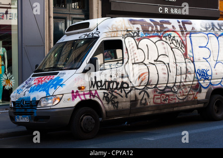 An urban scene with a white van sprayed painted with graffiti. Stock Photo