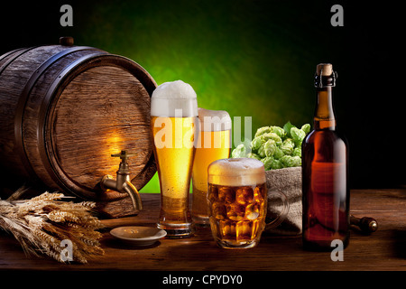 Beer barrel with beer glasses on a wooden table. The dark green background. Stock Photo