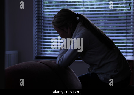 Profile of a girl with a ponytail, sitting hands covering her face. Silhouette. Stock Photo