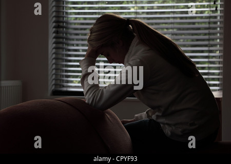 Profile of a girl with a ponytail, sitting hands covering her face. Silhouette. Stock Photo