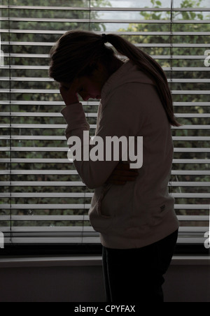 Profile of a girl with a ponytail, hands covering her face. Silhouette. Stock Photo