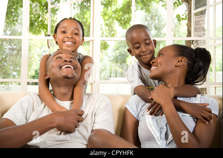 Young African married couple play with their two children on a couch Stock Photo