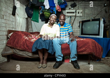 African couple sits together on a bed indoors Stock Photo