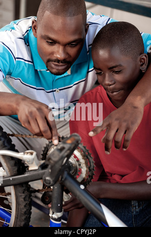 African Father and son working on a bicycle Stock Photo