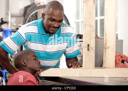 African father and son making measurements in a workshop Stock Photo