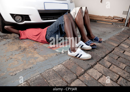 African father and son work on a car engine together Stock Photo