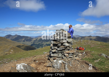 Walker at the cairn at the summit of Maol Chinn-dearg, the fourth Munro top on the South Glen Shiel Ridge from east to west Stock Photo