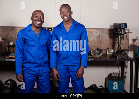 Two African mechanics standing in a workshop smiling at the camera Stock Photo